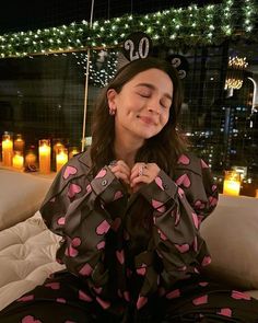 a woman sitting on top of a couch wearing pajamas and a tiara with hearts