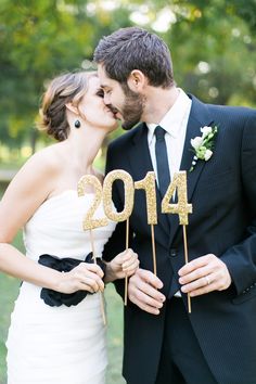 a newly married couple kissing in front of a cake topper with the number 2014 on it