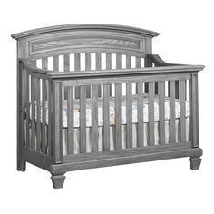 a gray crib with white sheets on the top and bottom rails, in front of a white background