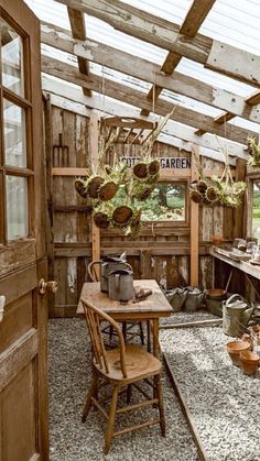 an outdoor kitchen area with wooden walls and tables, potted plants hanging from the ceiling