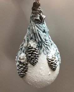 a snowman ornament hanging from a christmas tree with pine cones on it