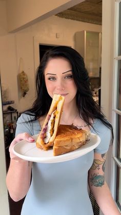 a woman holding a plate with a sandwich on it