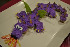 purple cupcakes with sprinkles and decorations on a white platter