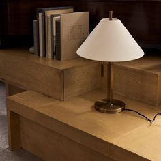 a lamp sitting on top of a wooden table next to a book shelf with books