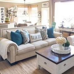 a living room filled with lots of furniture and pillows on top of a table in front of a window