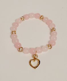 Rose quartz is known as the stone of love and reconcilliation and is customarily used as a gift of love.   It is thought to make one open to love and compassion.  Some believe that rose quartz has calming effects and helps to develope strong friendships. Two styles of bracelets are shown : # 1 - 8mm genuine rose quartz beads  with silver & rhinestone accent bands and an open silver heart charm.  #2- 8 mm genuine rose quartz beads with rose gold & rhinestone accent clusters and an open rose gold heart charm. Rose quartz is typically a cloudy translucent pink colour.  These bracelets are sure to plesse with its delicate colour of pink and silver or gold accents. This stretch rose quartz bracelet is made with natural pink rose quartz stones that have been polished to a glossy finish. It featu Gold And Pink Bracelet, Pink And Gold Bracelet, Pink Jewelry For Meditation, Pink Natural Stones Jewelry For Friendship, Pink Rose Quartz Gemstone Beaded Bracelets, Pink Rose Quartz Gemstone Bracelets, Pink Rose Quartz Bracelets For Meditation, Pink Natural Stone Bracelets For Friendship, Pink Spiritual Charm Bracelet For Friendship