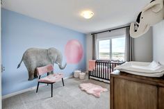 a baby's room decorated in pink and gray with an elephant mural on the wall