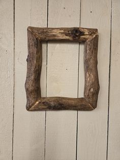 an old wooden frame hanging on the side of a white painted wood paneled wall