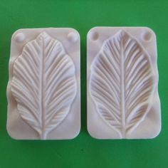 two white molds with leaves on them sitting next to each other, one in the shape of a rectangle