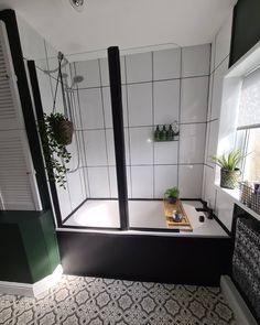 a bathroom with tiled walls and flooring has a plant in the bathtub next to it