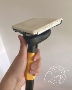 a hand holding a yellow and black hair dryer in front of a white wall