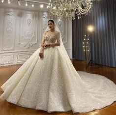 a woman in a wedding dress standing on a wooden floor with a chandelier