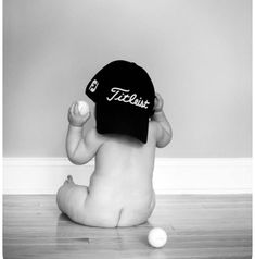 a black and white photo of a baby sitting on the floor playing with a ball