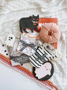 a pile of halloween decorations on top of a white blanket with an orange pumpkin and black cat