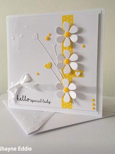 a white card with yellow and white paper flowers on it, sitting on top of a table