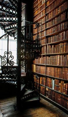 a spiral staircase in front of a bookshelf filled with lots of bookcases