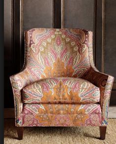 an upholstered chair with a colorful paisley pattern on the armrests and back