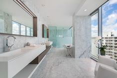 a large bathroom with marble walls and floor to ceiling windows overlooking the cityscape