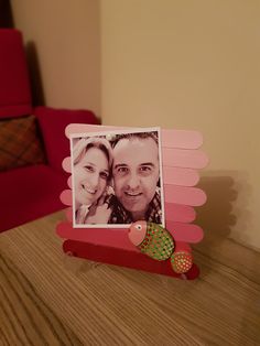 two people are posing for a picture in a photo frame on a table with a red chair behind them