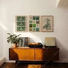 an old record player sits on top of a wooden cabinet in front of three framed posters