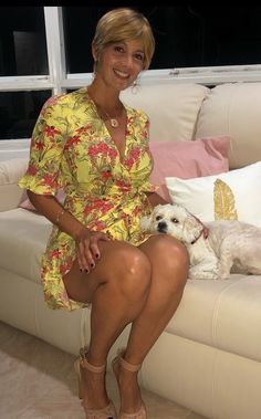 a woman sitting on a couch next to a white dog