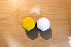 two small white and yellow objects sitting on top of a wooden table next to each other