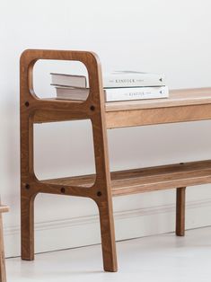 a wooden bench sitting next to a table with two books on it and a stack of books