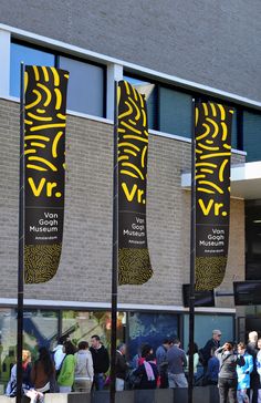 people are standing in front of a building with three large banners on the side of it