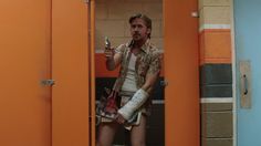 a man with bandages on his arm holding a cell phone in an orange locker room