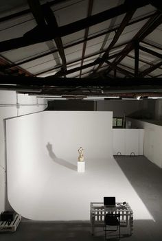 an empty room with a small table and chair in the center, on which there is a white backdrop