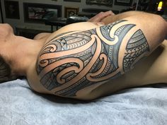 a man laying on top of a bed with a tattoo on his arm and shoulder