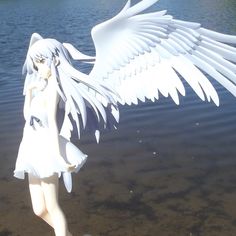 a white angel statue standing in front of a body of water with its wings spread out