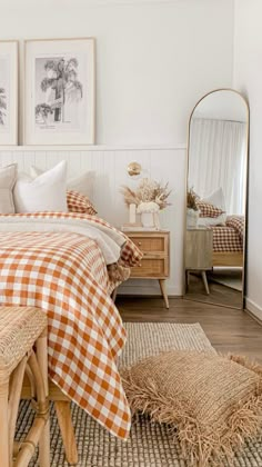 a bed room with a neatly made bed next to a mirror and two pictures on the wall