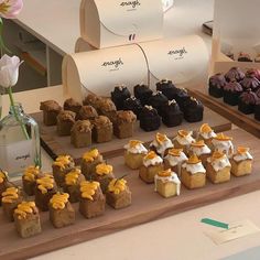 an assortment of desserts displayed on a wooden tray in front of a vase with flowers