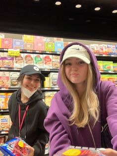 two young women are shopping in a grocery store and one is wearing a purple hoodie