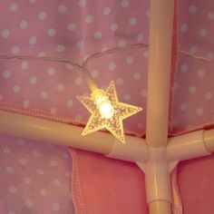 a star shaped light sitting on top of a pink bed sheet covered in white polka dots