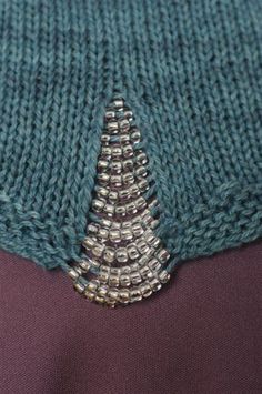 a close up view of a knitted sweater with beads on the bottom and side