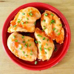 some food is in a red bowl on a wooden table and ready to be eaten