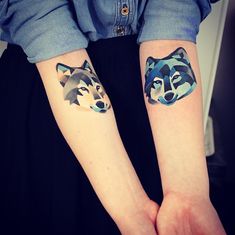 two people with matching tattoos on their arms, one has a wolf and the other has a dog