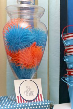 there is a vase filled with blue and orange balls on the table in front of other red, white and blue decorations