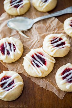 cookies with white icing and raspberry toppings on brown paper next to spoon