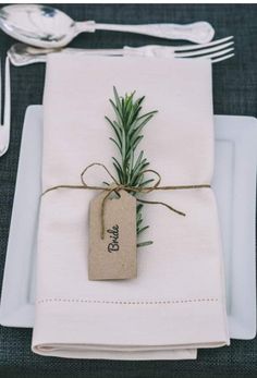 a place setting with napkins, silverware and an empty tag tied to it