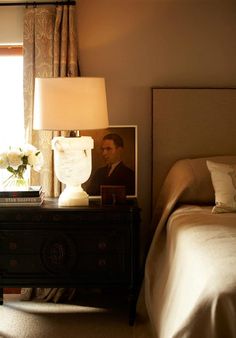 a bed room with a neatly made bed and a night stand next to a window