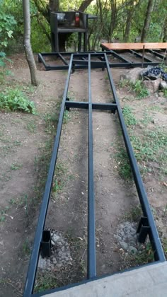 an old train track in the middle of some dirt and grass with trees behind it