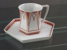 a red and white coffee cup sitting on top of a plate