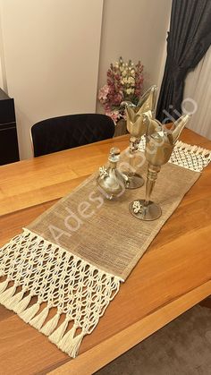 a wooden table topped with two vases filled with flowers next to a lace runner