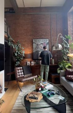 a man is standing in the living room looking at something on the wall behind him