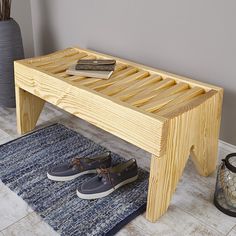 a wooden bench sitting on top of a blue rug next to a pair of shoes