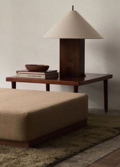 a lamp sitting on top of a wooden table next to a couch and coffee table