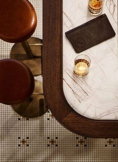 a marble topped table with two glasses on it and a leather wallet next to it